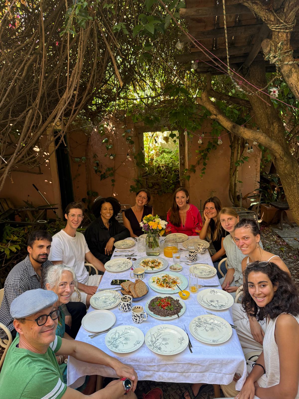 Community gathering around a table sharing a meal outdoors