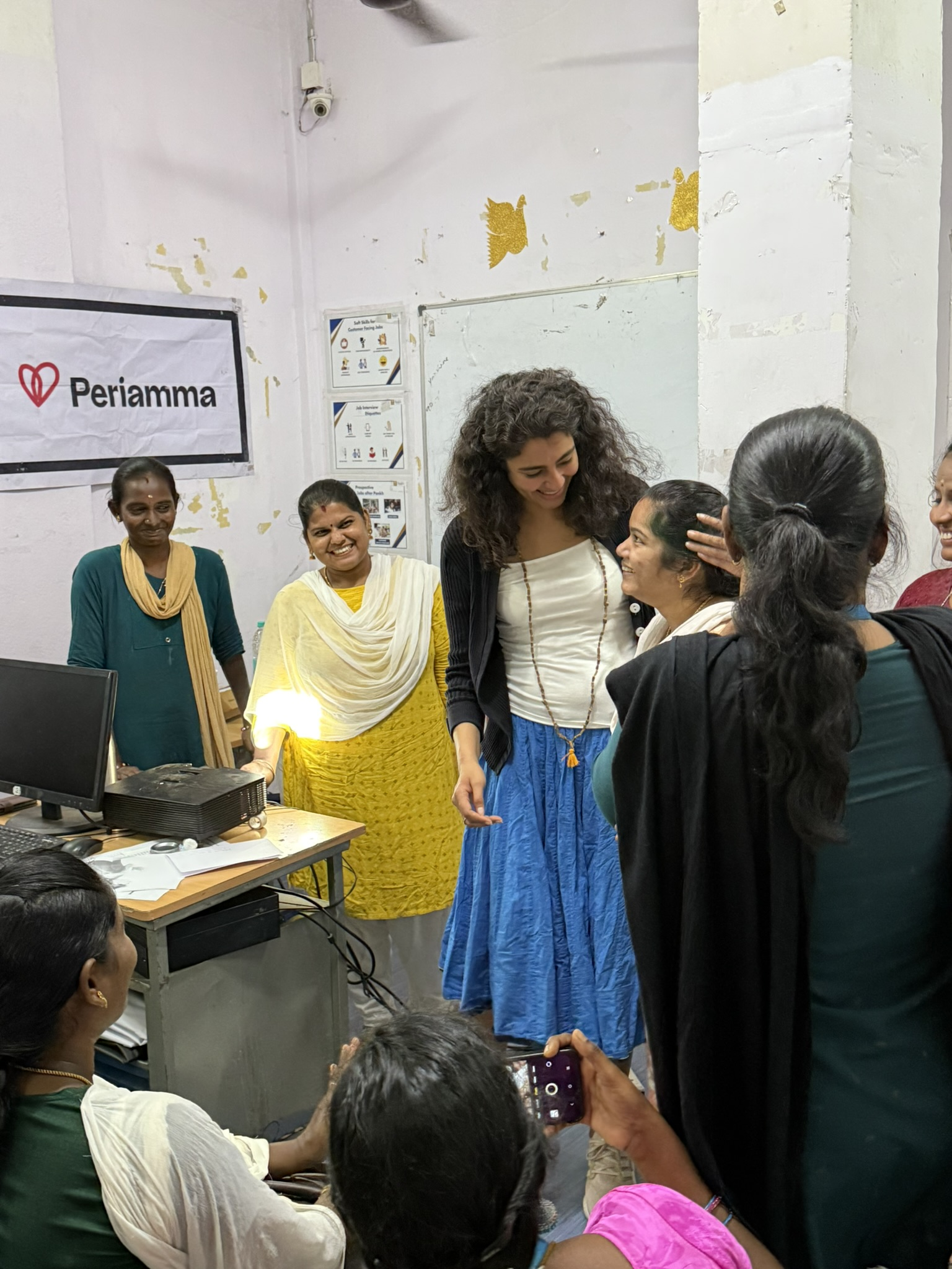 Women gathering in Periamma office with logo on screen